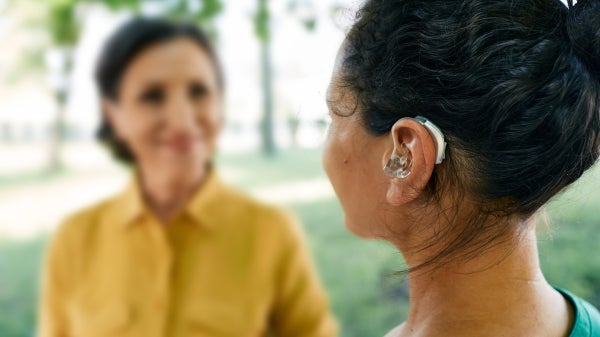 Woman wearing a hearing aid while talking to her friend