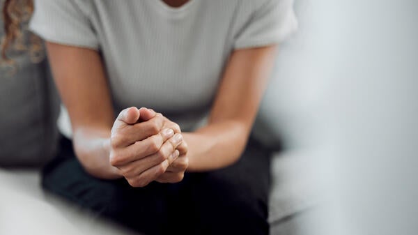 Woman sitting on couch with hands clasped