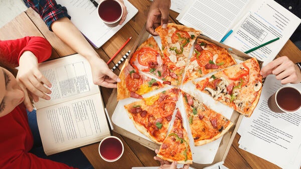 An overhead shot of hands pulling pizza slices off a platter