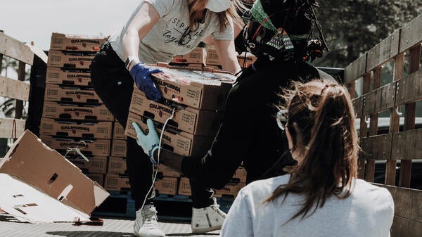 woman wearing a mask, unloading food from a truck