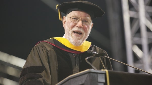 commencement speaker at podium addressing graduates 