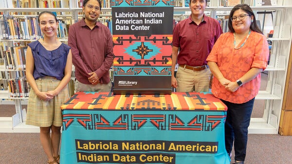 Four people standing around a table and smiling for the camera