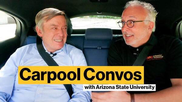 Two men sitting in the backseat of a car talking.