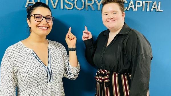 Two people smiling and pointing to a sign on a wall that reads "Lix|Cap Advisory Capital."