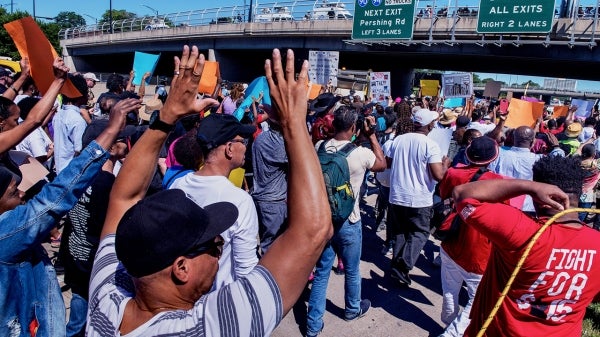 Black Lives Matter protesters carrying signs walk under a freeway overpass in Chicago