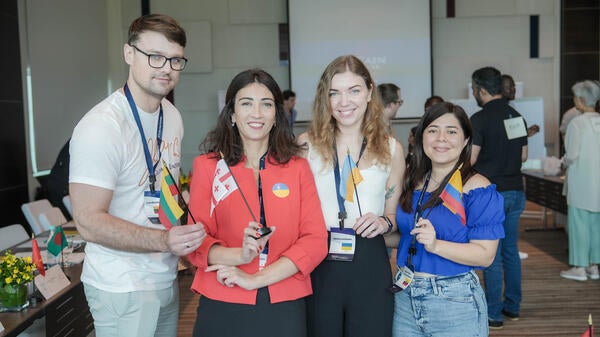 Group of four people posing for a photo, holding ID badges and smiling.