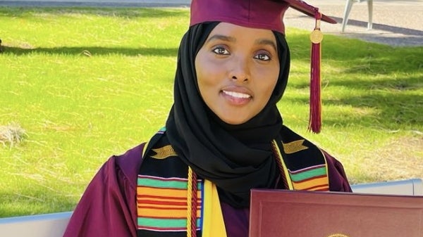 ASU student Maryam Abdulle poses for a photo in a graduation gown and cap, holding her diploma cover