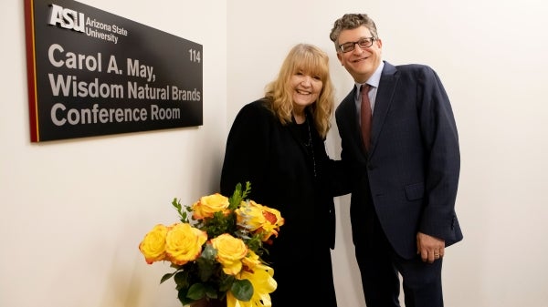 two people posing next to conference room sign