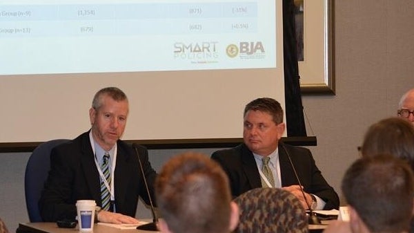 two men at table discussion in front of audience