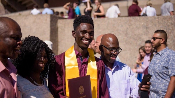 Black student celebrating graduation with family