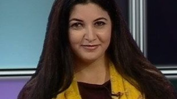 Associate Professor of Arabic Miral Mahgoub al-Tahawy smiles in a professional headshot. She has long thick black hair and is wearing a dark shirt with a yellow scarf.