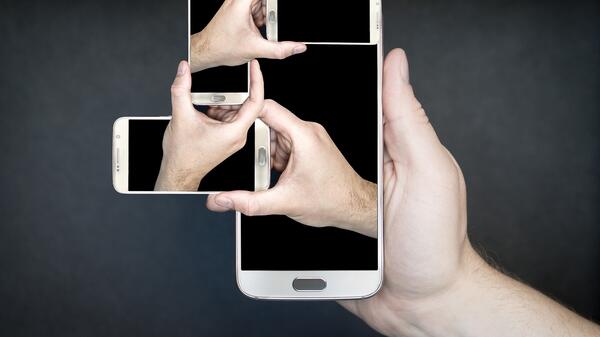 Abstract photo illustration of several hands holding several smartphones.