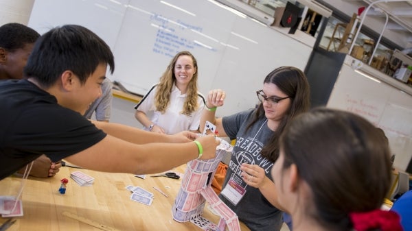 Students build a card tower. 