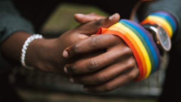 Rainbow ribbon wrapped around a Black person's hands.