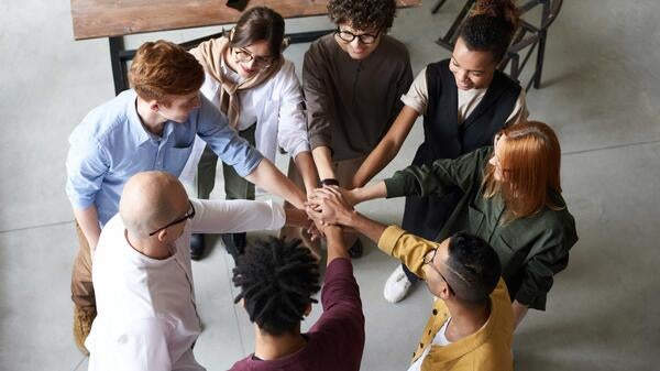 Diverse coworkers putting hands together in a circle