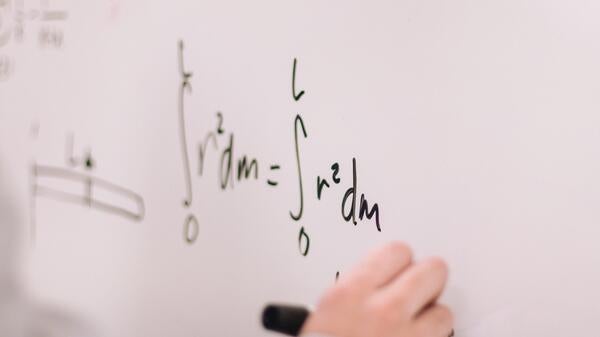 Person writing equations on white board