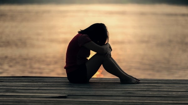 Girl sitting on dock with head down on knees