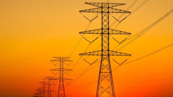 Power lines silhouetted against an orange sky