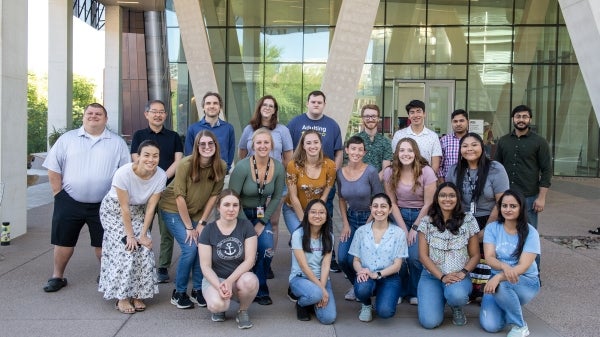 A group of people pose together in front of a building.