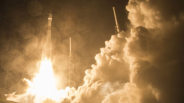 Columns of smoke erupt as a rocket launches into the night sky. The caption reads: A rocket launch at Cape Canaveral, Florida. Photo Credit: NASA/Aubrey Gemignani.