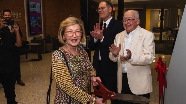 A woman uses an oversize pair of scissors to cut a ribbon at a ceremony