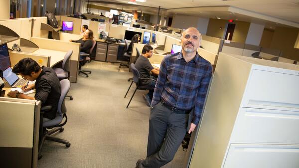 K. Selcuk Candan poses near students working in cubicles.