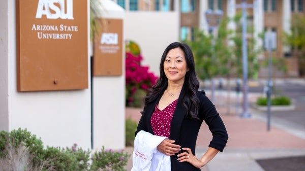 Samantha Casselman poses with her white nurse practitioner coat by ASU's Mercado Building on the Downtown Phoenix campus