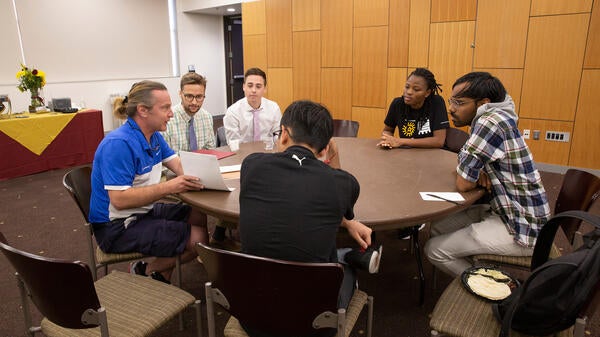 A group of students and an engineer sitting around a table.