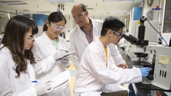 Student scientists work with a professor in an engineering lab.