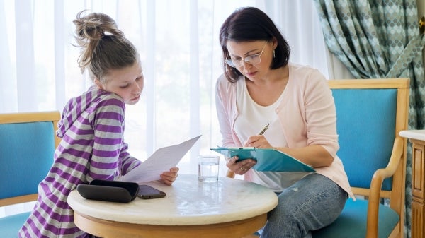 Young girl seated at a table with a social worker going over papers.