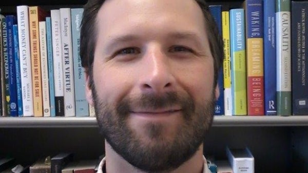 Portrait of ASU Professor C. Tyler DesRoches with books in background