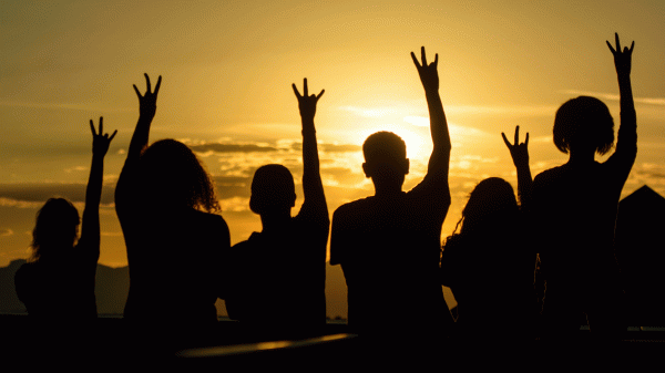 A group of students is silhouetted against a sunset