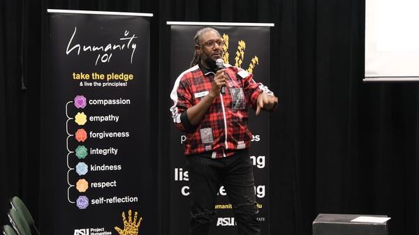 Man standing in front of event signage giving a speech.