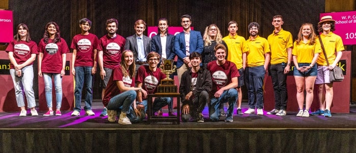 Teams of students stand on a stage