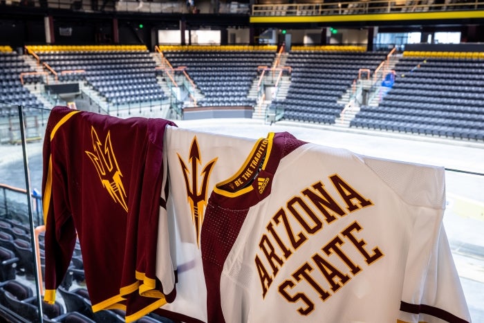 ASU hockey jerseys hang on glass wall at arena