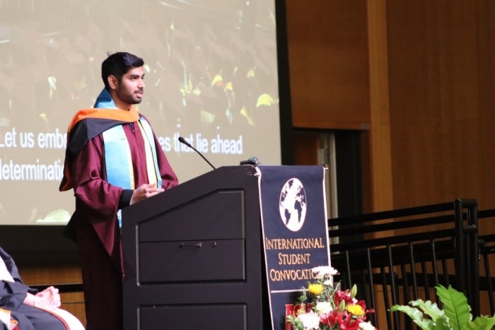 Man standing behind a lectern speaking into a microphone at ASU's International Student Stole Ceremony.