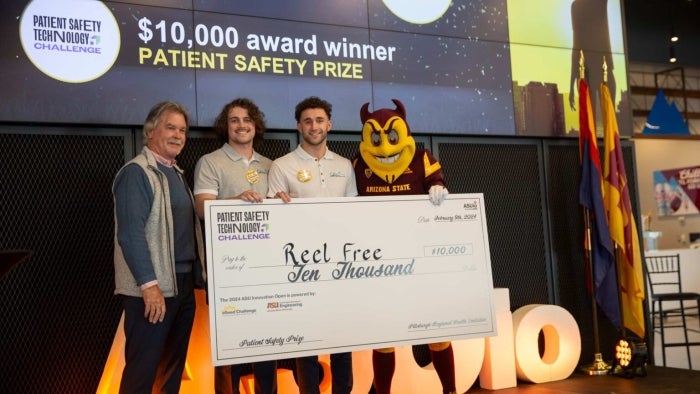 People smiling and holding a large check.