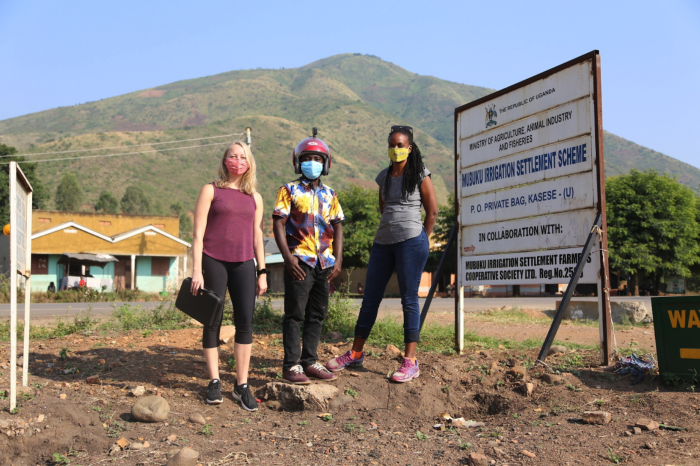 Three people pose for photo next to slide in Uganda