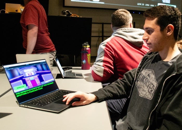 Man seated at a table working on a laptop.