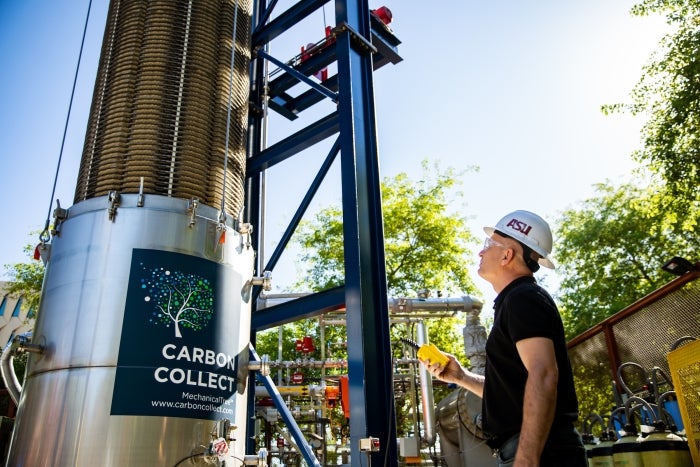 A man in a construction hat stands in front of the MechanicalTree.