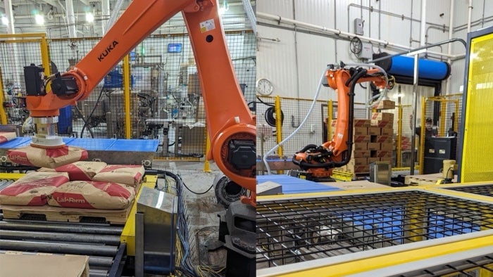 An industrial robot picks up 50 pound bags and 40 pound boxes of dry yeast.