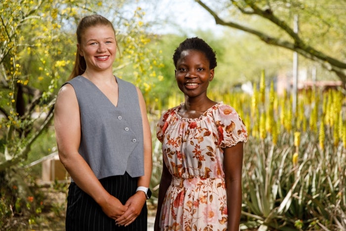 Colley and Sakala stand together outside in front of a desert landscape garden.