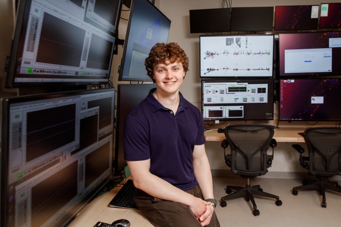 Adam Kurth sits on a desk in the Biodesign lab