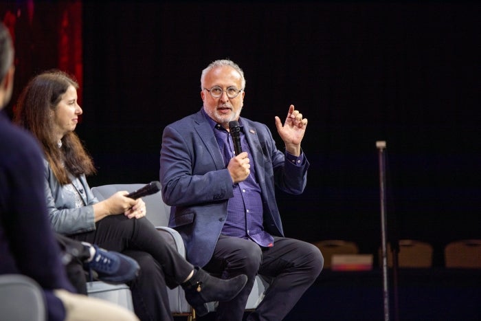 Man speaking on stage as part of panel