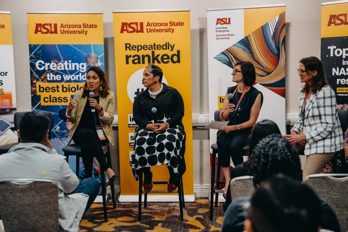 Four women speak in front of an audience