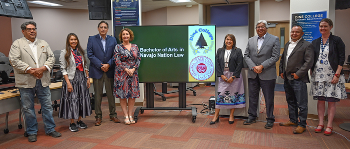 A line of people take a group photo by a sign that says Bachelor of Arts in Navajo Nation law