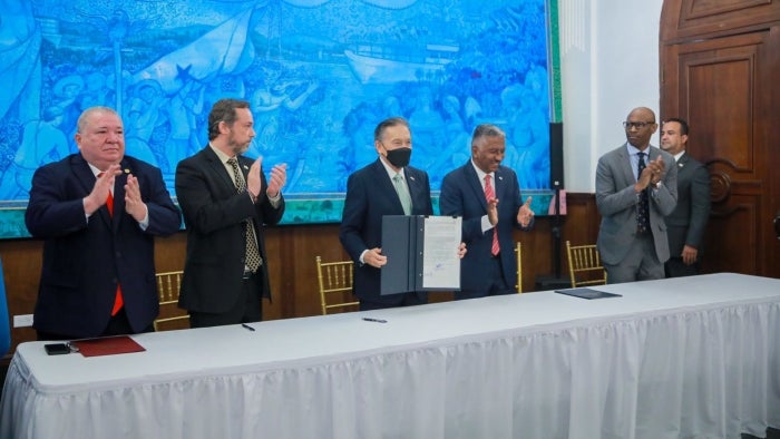 People stand and clap while holding up a signed document