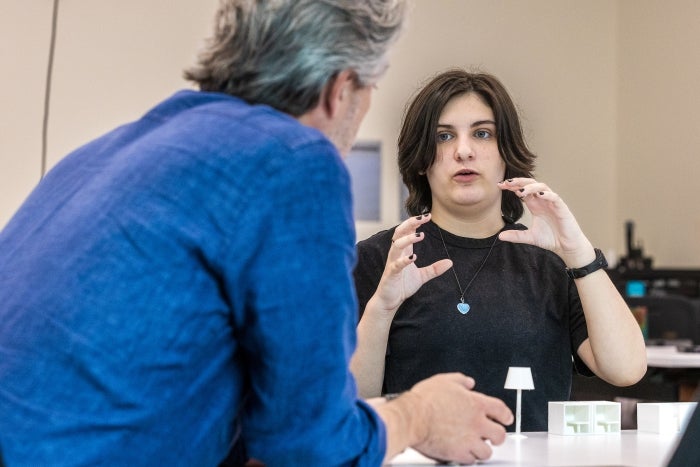 A student gestures while sitting at a table 