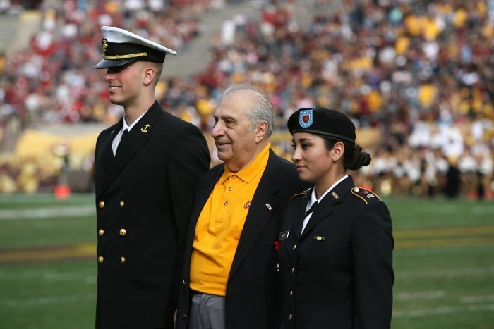 Gregory Melikian on the football field while being recognized for his military service during WWII.