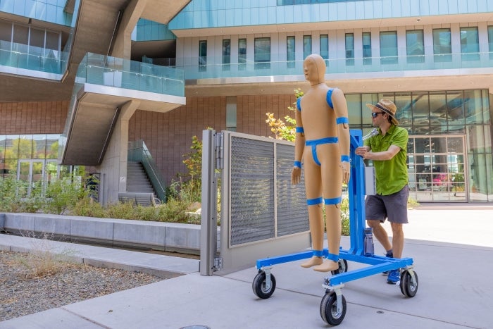 Konrad Rykaczewski pushes ANDI on a blue wheeled frame at the Rob and Melani Walton Center for Planetary Health for some outdoor calibration.